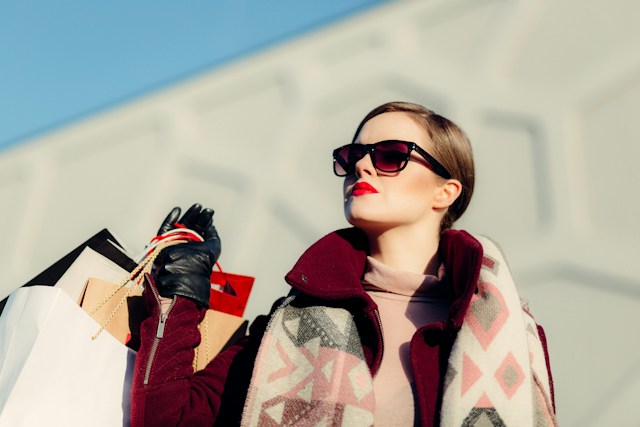 Woman carrying shopping bags and thinking about moving to cities with vibrant fashion scenes